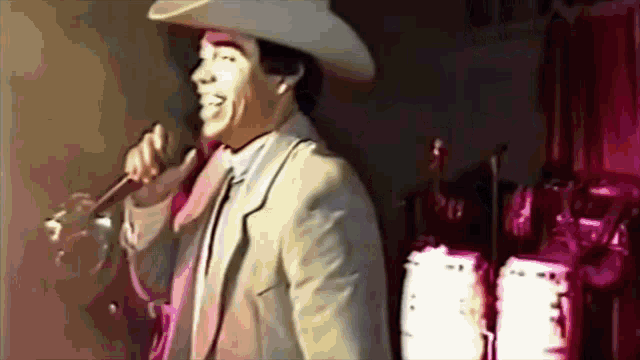 a man in a suit and cowboy hat singing into a microphone