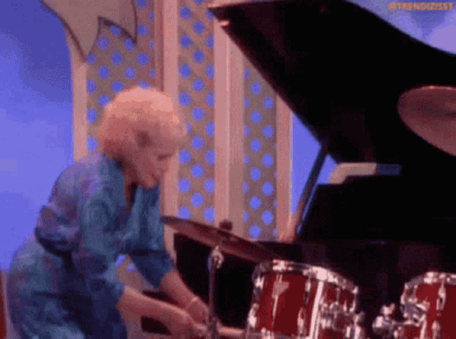 a woman in a blue dress is playing drums on a stage .