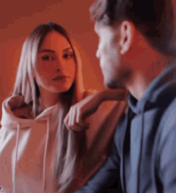 a man and a woman are looking at each other and the woman is looking at the man 's face .