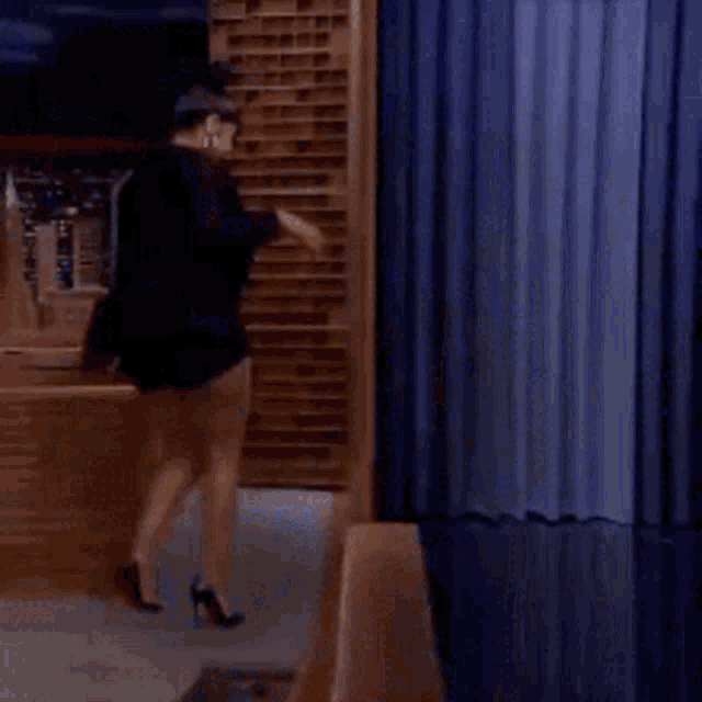a woman in shorts stands in front of a blue curtain