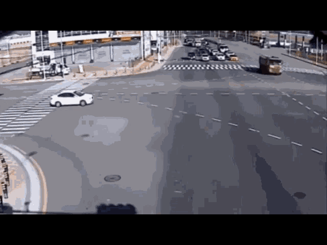 a white car is driving through a busy intersection with a yellow truck