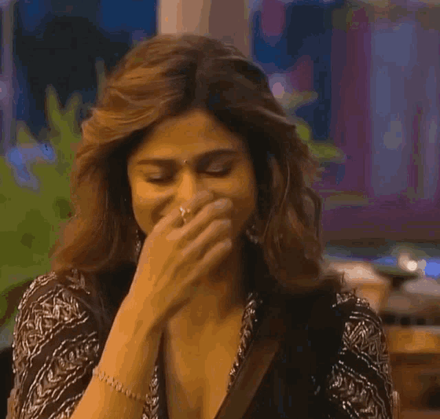 a woman is covering her mouth with her hand while wearing a bracelet