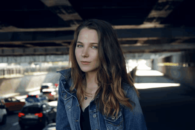 a woman in a denim jacket stands in a tunnel