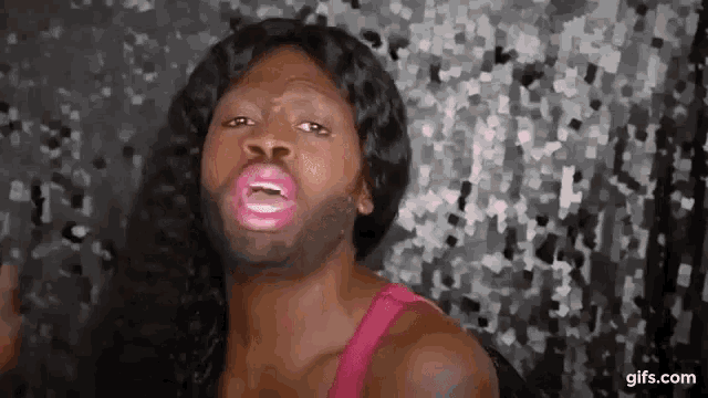 a man with long hair and a beard is wearing a pink tank top .