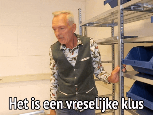 a man in a green vest is standing in front of a shelf that says het is een vreelijke klus