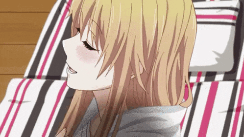 a close up of a blonde anime girl laying on a striped couch .
