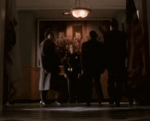 a group of people standing in front of a painting of a crowd