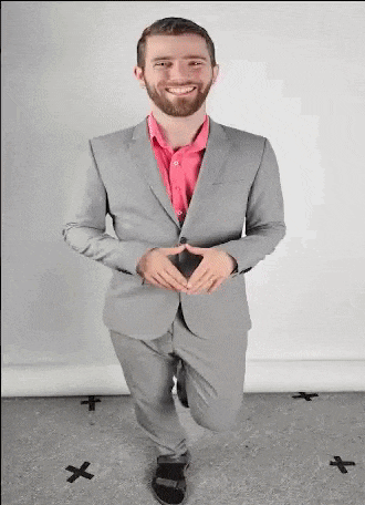 a man in a suit and a red shirt is kneeling down and smiling .