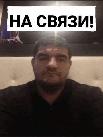 a man with a beard is sitting in front of a sign that says ha cba3i