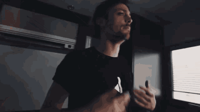 a man wearing a black shirt with the letter a on it is making a funny face