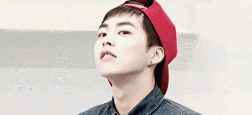 a young man wearing a red hat and denim shirt is looking up .