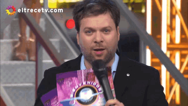 a man holding a microphone with eltrecetv.com written on the bottom
