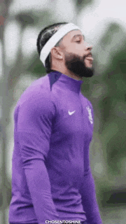 a man with a beard wearing a headband and a purple shirt .