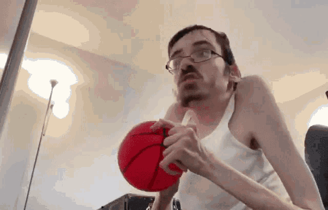 a man with glasses is holding a red basketball in his hands