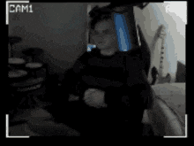 a man is sitting in front of a camera with cam1 on the corner