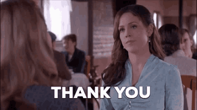 a woman is sitting at a table in a restaurant talking to another woman and saying `` thank you '' .