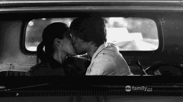 a black and white photo of a man and woman kissing in a car with abc family hd written on the side