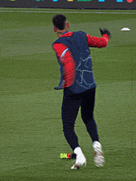 a man in a blue vest kicks a soccer ball in front of a sign that says foundation