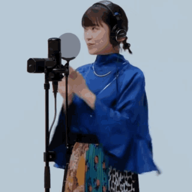 a woman in a blue shirt is singing into a microphone .