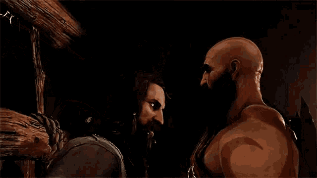 two men are standing next to each other in a dark room .