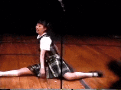 a girl in a plaid dress is doing a split on a stage in front of a microphone