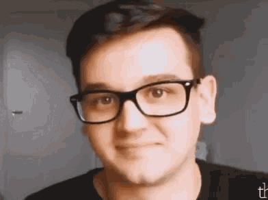a young man wearing glasses and a black shirt is smiling for the camera .