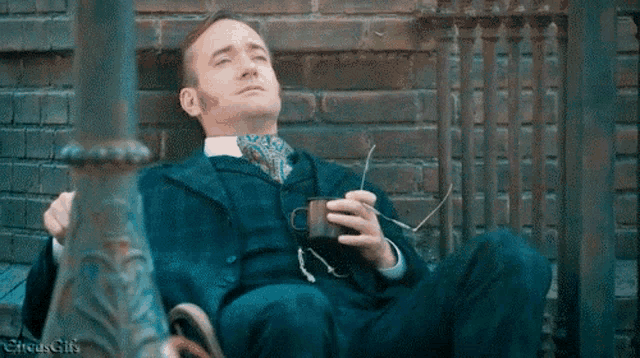 a man in a suit and tie is sitting on a bench holding a cup of coffee