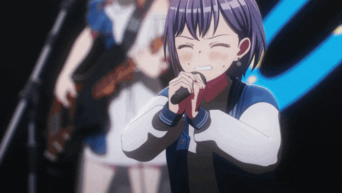 a girl is singing into a microphone in front of a guitar player
