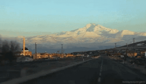 a road with a mountain in the background and a mosque on the left