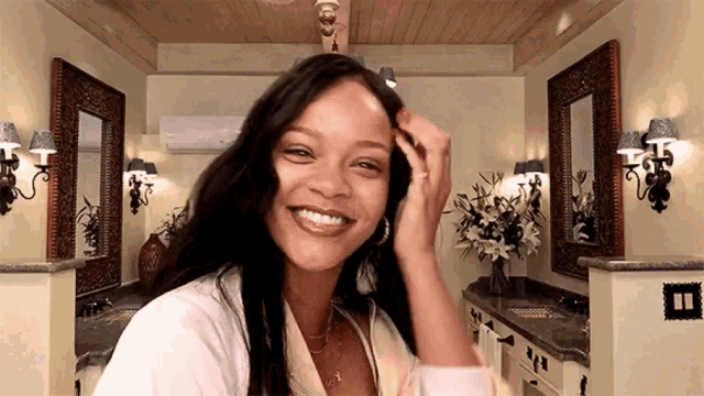 a woman is smiling in a bathroom with two mirrors and flowers .