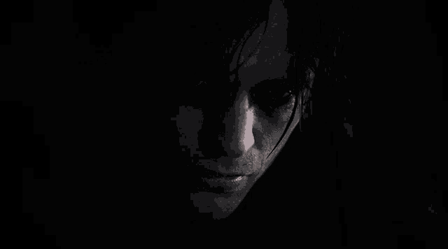 a close up of a man 's face in the dark with a black background .