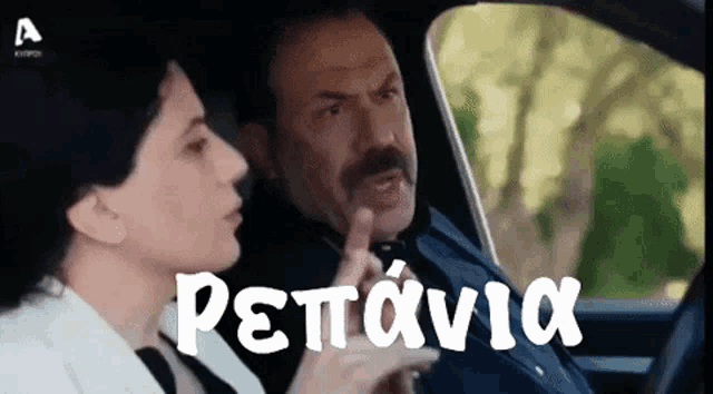 a man and a woman are sitting in a car and the man is pointing at the woman in greek