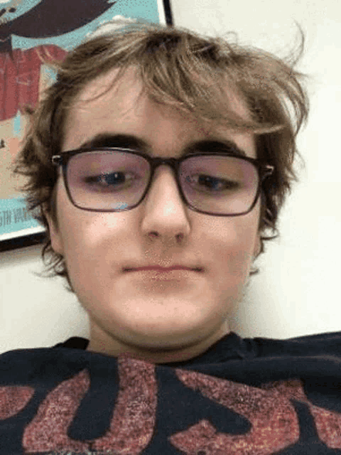 a young man wearing glasses and a t-shirt is making a face .