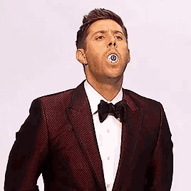 a man in a suit and bow tie has a sticker on his mouth that looks like an eye