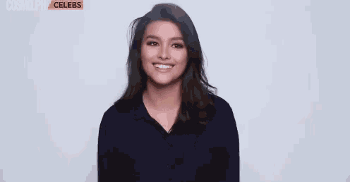 a woman in a black shirt is smiling and making a funny face .