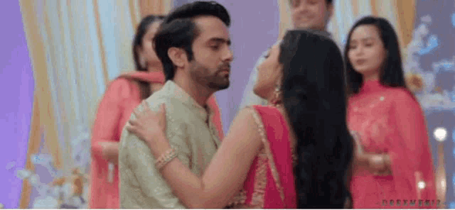 a man and a woman are hugging each other in front of a crowd of people .