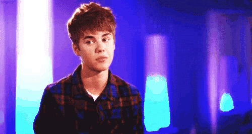 a young man in a plaid shirt is standing in front of a purple and blue background .