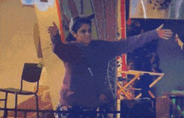 a woman giving a thumbs up with a purple sweatshirt that says ' i love you ' on the back