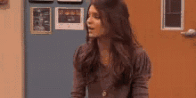 a woman with long hair is standing in front of a door and a sign that says ricky .