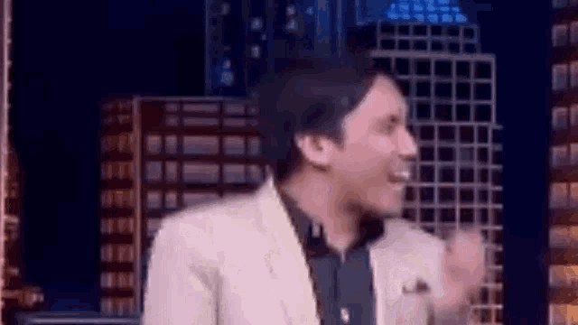 a man in a suit is standing in front of a city skyline and laughing .