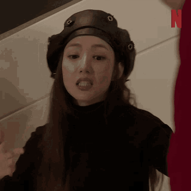 a woman wearing a hat and a black turtleneck is making a funny face