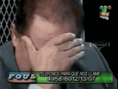 a man covering his mouth with his hands in front of a sign that says " foul "