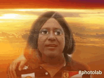 a woman is wearing a ferrari shirt and has a sunset in the background .