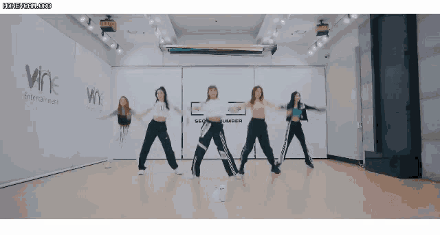 a group of women are dancing in a room with a sign that says wne