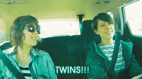 two women are sitting in the back seat of a car and one of them is saying " twins "
