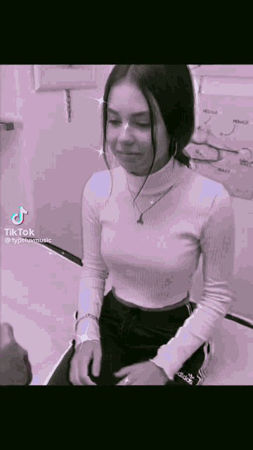 a girl wearing a white turtleneck and black adidas pants is sitting in a chair