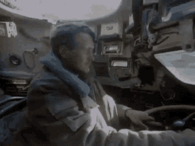 a man in a jacket is driving a vehicle with a sign on the wall that says ' a ' on it