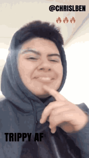 a man wearing a hoodie is making a funny face and the caption says trippy af