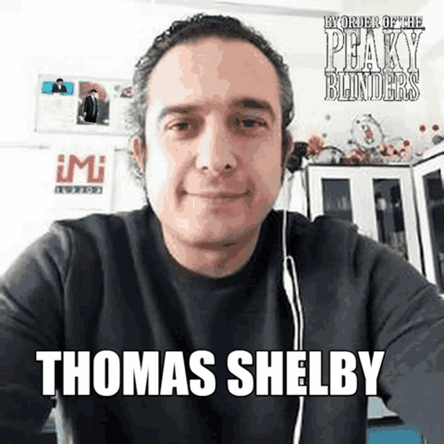 a man is wearing headphones and taking a selfie with the name thomas shelby on it .