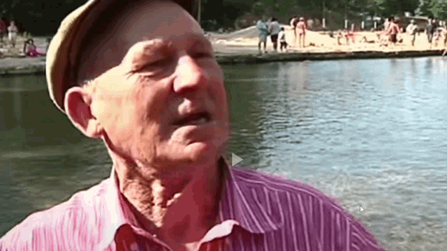 a man in a hat is standing in front of a lake
